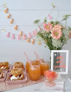 a table topped with desserts and drinks on top of a white table covered in flowers