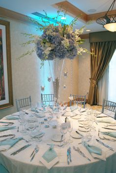 the table is set with silverware and flowers in tall vases on each side