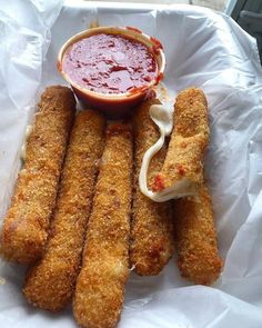 some fried food is sitting in a basket with dipping sauce on the side and ketchup