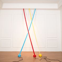 two colorful objects are on the floor in an empty room with white walls and wood floors