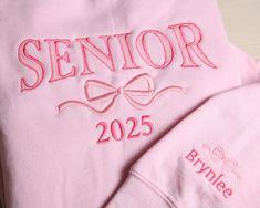 "This cute and comfy sweatshirt is a great gift choic for any high school or college senior or grad. Available in various sizes, two styles (crewneck and hoodie) and multiple colors. Option to customize the sleeve with a name, school, initials, etc.  Perfect gift for birthday, holidays and graduation. Grad Gift, New Grad Gift, Graduation Sweatshirt, College Graduation, Graduation Gift, High School Graduation, Christmas gift for Grad, Senior Night \"SENIOR\" will be embroidered in the preppy arch Diy Senior Sweatshirt, Senior Backpacks Funny, Senior Year Sweatshirts, Senior Diy Projects, Senior Hoodies Design Ideas 2025, Senior Crewneck Ideas, Senior Jersey Ideas, Senior Year Outfits High Schools