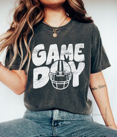 a woman wearing a game day shirt and jeans