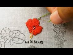 someone is stitching a red flower on a piece of fabric with the word missus