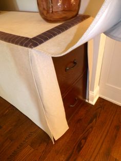 a brown vase sitting on top of a wooden dresser next to a white table cloth