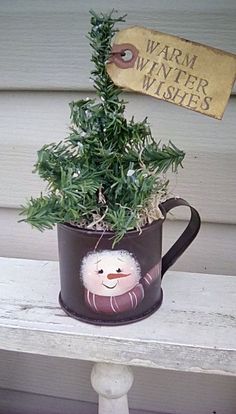 a potted plant sitting on top of a wooden bench next to a sign that says warm winter wishes