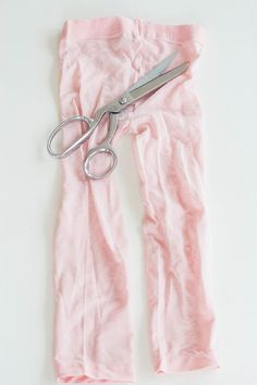 a pair of scissors sitting on top of pink pants