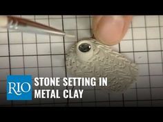 a person holding a metal clay object with a needle in it's mouth and the words, stone setting in metal clay