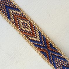 a blue and brown beaded bracelet on a white surface with an orange diamond design