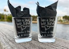 two shot glasses with black napkins in front of water