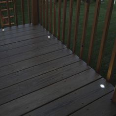 a wooden deck with lights on it and grass in the background