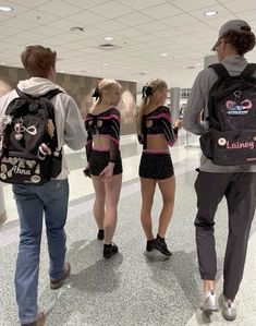 three people are walking through an airport with backpacks on their backs and one person is carrying a back pack