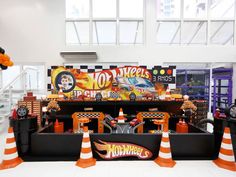 an assortment of toy cars on display in a room with orange and white striped cones