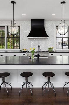 a kitchen with an island and four stools in front of the countertop area