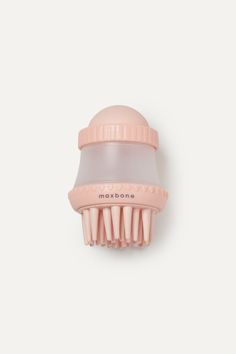 a pink hair brush sitting on top of a white wall