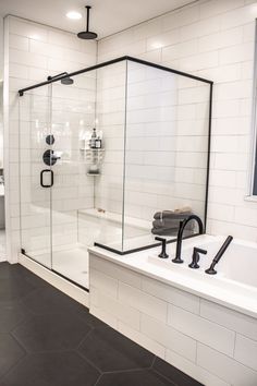 a bathroom with a walk in shower next to a white bathtub and black faucet