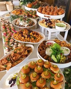 a buffet table filled with lots of different types of food on white plates and serving platters