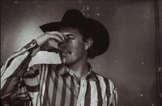 a man in a striped shirt drinking from a bottle with his hands to his face