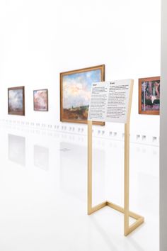 a white room with paintings on the wall and a wooden stand in front of it