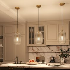 a kitchen with marble counter tops and hanging lights