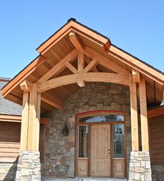 the front entrance to a home with stone pillars and wood trimmings on it