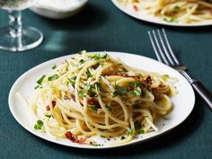 pasta with bacon and parmesan cheese on a white plate next to silverware