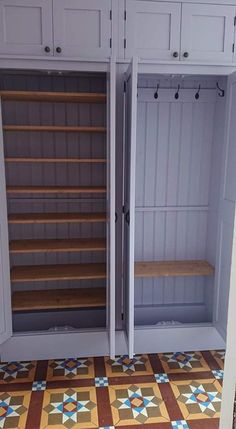 two white cupboards with wooden shelves in the middle and tiled flooring next to them