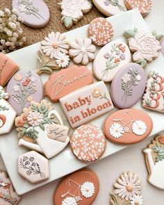 decorated cookies are arranged on a plate with the words baby in bloom written on them