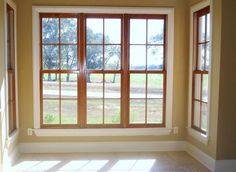 an empty room with three windows and tile flooring