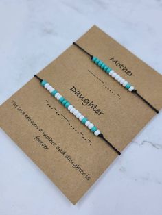 two blue and white beaded bracelets sitting on top of a card