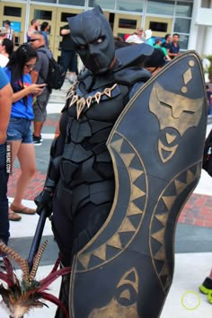 a man dressed up as batman standing in front of a group of people on the street