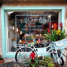 a bicycle parked in front of a flower shop with plants on the outside and inside