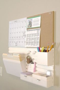 a bulletin board mounted to the side of a wall next to a drawer filled with office supplies