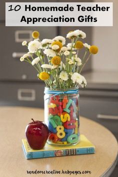 a jar filled with lots of colorful letters next to an apple on top of a table