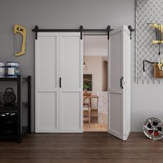 an open door leading to a kitchen and dining room with white walls, wood flooring and black accents