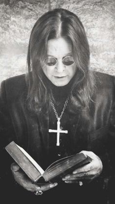 a woman with glasses holding a book in her hands and wearing a cross on it