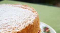 a cake with powdered sugar on top sitting on a plate next to a fork