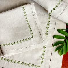 two white linens with green embroidered designs on them