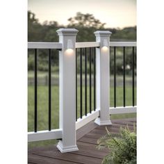 two white pillars on a deck with grass and trees in the background