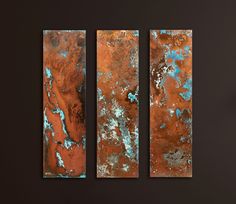 three pieces of metal with rust and blue paint on them, hanging from a wall