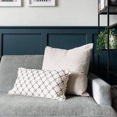 a couch with two pillows on top of it next to a book shelf filled with books