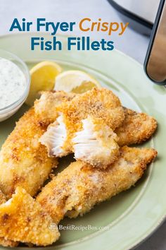 air fryer crispy fish fillets on a green plate with lemon wedges