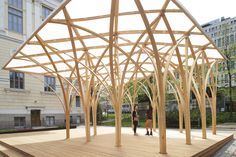 two people are standing under a wooden structure