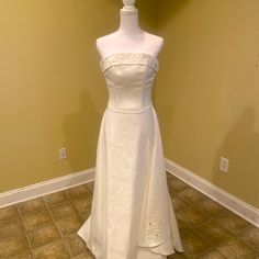 a white wedding dress on display in a room with tile flooring and yellow walls