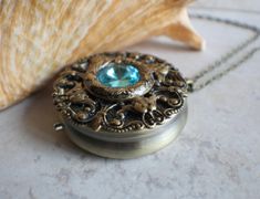 "Turquoise rivoli crystal music box pendant. This round music box pendant is inspired by the gorgeous music box pendants of era's gone by. Music box is pill box size, please look at the dimensions for exact size. A perfect round bronze locket has been adorned with layers of bronze filigree and Turquoise Rivoli Crystal in the center. The bronze filigree layers have been sealed in a clear resin to give a glass like finish and preserve the beauty of this musical pendant. The music box winds from a Music Box Necklace, Music Box Locket, Box Necklace, Music Box Jewelry, Turquoise Crystal, Black Gift Boxes, Necklace Box, Pin Jewelry, Crystal Charm