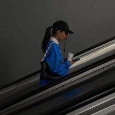 a woman is walking down an escalator with a cup in her hand