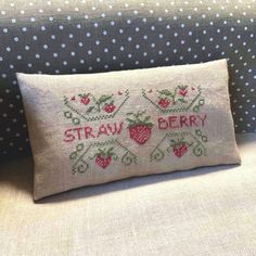 a cross stitched pillow with strawberries on the front and back, sitting on a couch