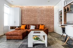 a living room filled with furniture and a brick wall behind the couch is a white coffee table