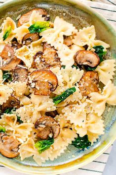 pasta with mushrooms, spinach and parmesan cheese in a bowl on a table