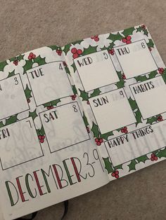 an open christmas planner with holly and red berries on the pages, sitting on carpet