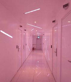 a long hallway with white walls and doors leading to another room on the other side